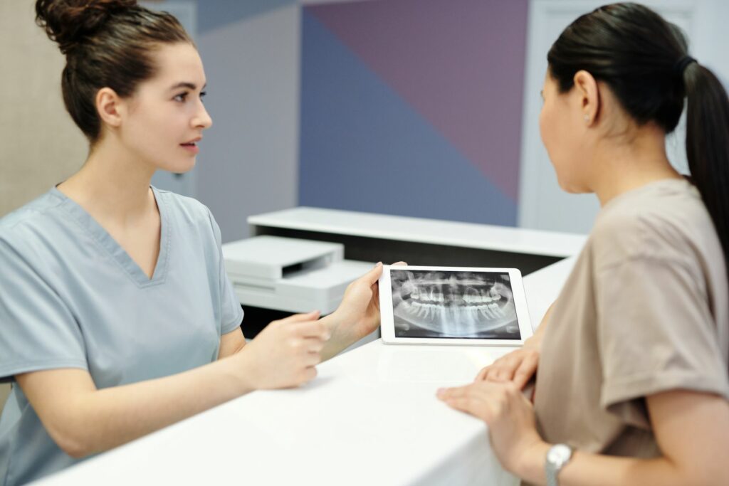 Chirurgien-dentiste montrant une radiographie dentaire à un patient avant une greffe osseuse