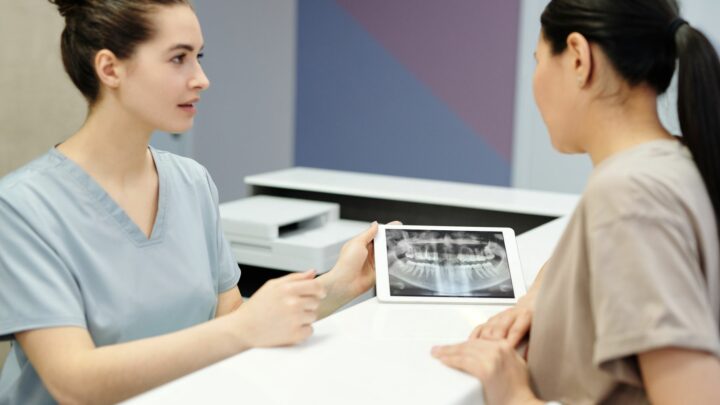 Chirurgien-dentiste montrant une radiographie dentaire à un patient avant une greffe osseuse